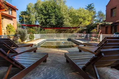 a patio with wooden benches and a swimming pool at La Cuyanita - Complejo de cabañas in Merlo