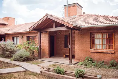 a brick house with a front porch with a bench at La Cuyanita - Complejo de cabañas in Merlo