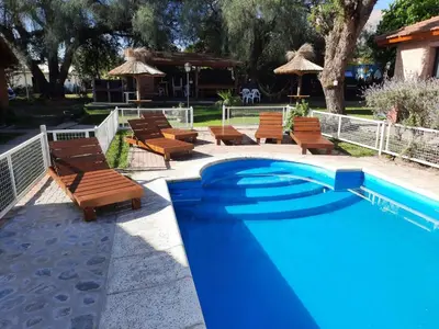 a swimming pool with chairs and a table and umbrella at La Cuyanita - Complejo de cabañas in Merlo