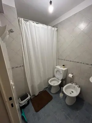 a white bathroom with a toilet and a sink at Departamento EL QUINTANAR 2 in Cordoba