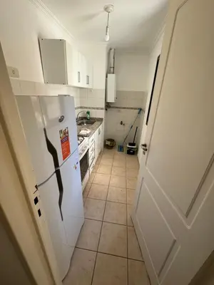 a kitchen with a white refrigerator and a tile floor at Departamento EL QUINTANAR 2 in Cordoba