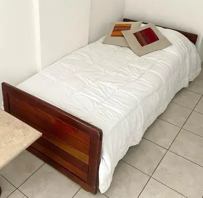 a bed with white sheets and pillows on it at Departamento Triana in Cordoba