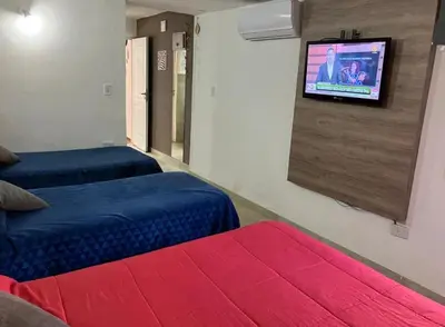 a room with two beds and a tv on a wall at Departamentos del Cerro in Cordoba