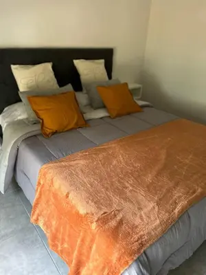 a bed with orange and gray pillows in a room at Sierras VGB Centro in Villa General Belgrano