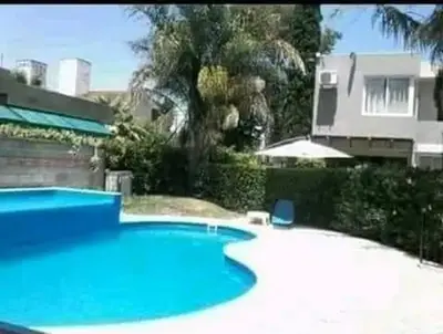 a large blue swimming pool in front of a house at Duplex Independencia in Villa Carlos Paz