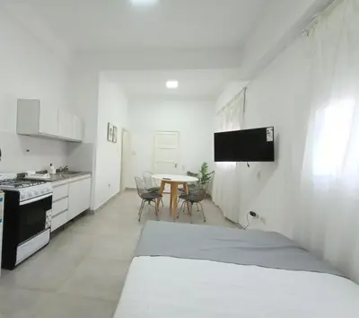 a white room with a bed and a table in it at Artigas Confort - Bienes Reales in Cordoba