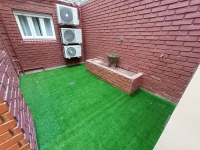 a backyard with green grass and a brick building at Artigas Confort - Bienes Reales in Cordoba