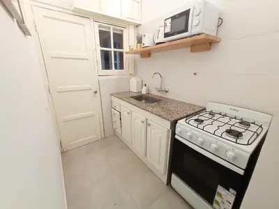a small kitchen with a stove and a microwave at Artigas Confort - Bienes Reales in Cordoba