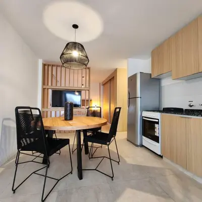a kitchen with a wooden table and black chairs at Loft en Güemes Piso 9 in Cordoba
