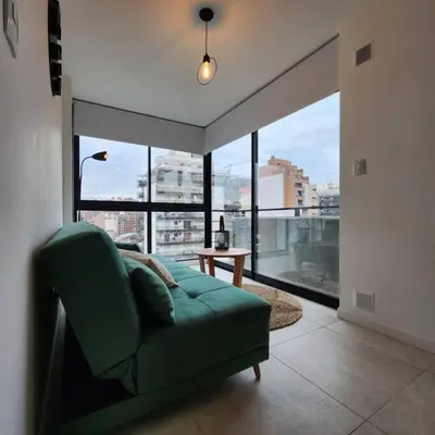 a living room with a green couch and a large window at Loft en Güemes Piso 9 in Cordoba
