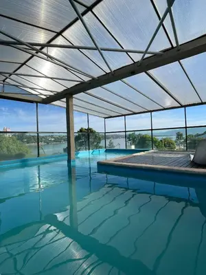 a large swimming pool with a roof over the water at Costalago Suites Hotel in Villa Carlos Paz