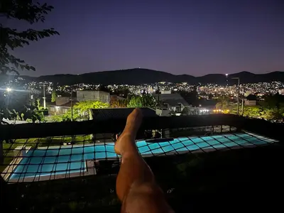 a person holding up a rail over a pool at night at Lago de montaña in Villa Carlos Paz