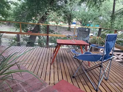 two chairs and a table on a wooden deck at Cabañas Aromas Serranos in Alta Gracia