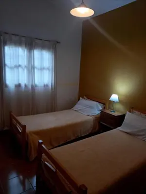two beds in a room with a window and a lamp at Cabañas Aromas Serranos in Alta Gracia