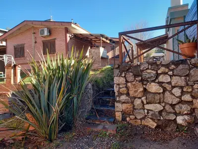 a stone wall in front of a house at Cabañas Aromas Serranos in Alta Gracia