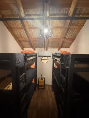 a room with three bunk beds and a ceiling at La Caballeriza Hostel in Tanti Nuevo