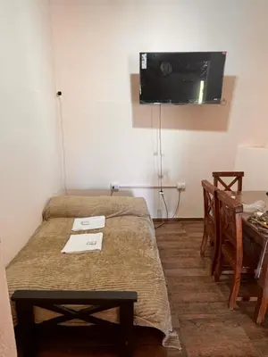 a room with two beds and a tv on the wall at La Caballeriza Hostel in Tanti Nuevo