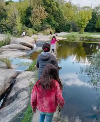 two people walking along a river near a pond at La Caballeriza Hostel in Tanti Nuevo