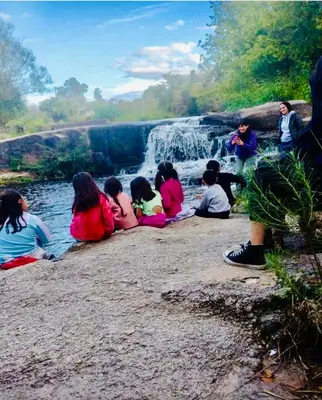 a group of children sitting next to a waterfall at La Caballeriza Hostel in Tanti Nuevo