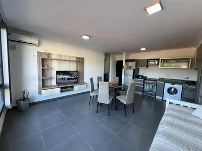 a kitchen and living room with a table and chairs at Edificio Stefano III - Departamento con cochera y amenities a pocas cuadras del centro in Villa Carlos Paz