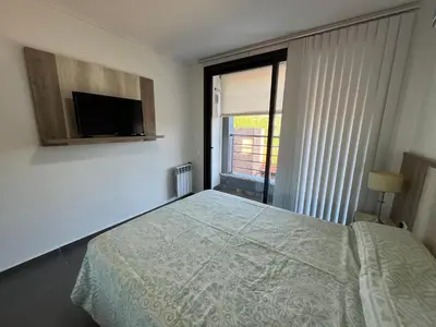 a bedroom with a bed and a tv and a window at Edificio Stefano III - Departamento con cochera y amenities a pocas cuadras del centro in Villa Carlos Paz
