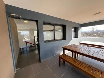 a room with a bench and a table and windows at Edificio Stefano III - Departamento con cochera y amenities a pocas cuadras del centro in Villa Carlos Paz