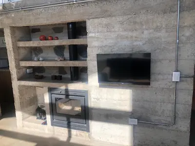 a stone fireplace with a tv and a fire place at Casa L in Los Reartes