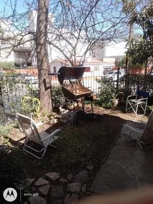 a grill and chairs in a yard next to a tree at Irupé in Villa Carlos Paz