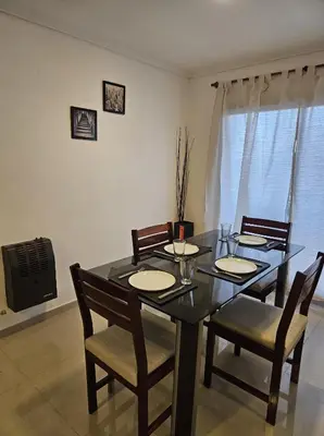 a dining room table with four chairs and a television at Hermoso y comodo departamento Hospital Cardiologico Kempes Centro de Conveciones Cordoba in Cordoba