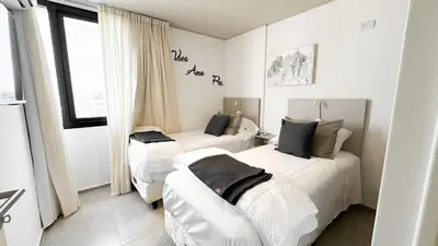 two beds in a room with white walls at SERIETÁ 2 dormitorios con pileta y terraza panoramica in Cordoba