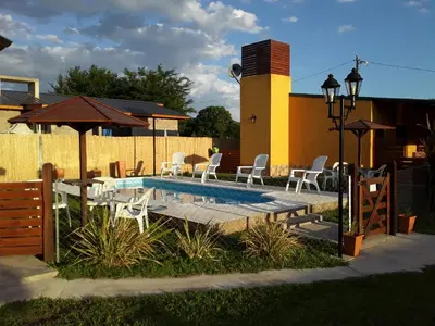 a swimming pool with chairs and a table and umbrella at Complejo Rancho Aparte in Villa Rumipal