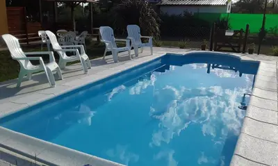 a blue swimming pool with chairs and a table at Complejo Rancho Aparte in Villa Rumipal