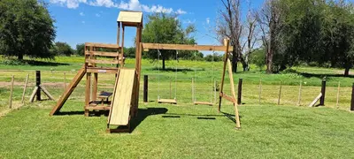 a wooden swing set in a field of grass at Ayres del Golf Posada-Restó in Merlo