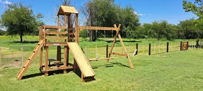 a wooden playground with a wooden ladder in a field at Ayres del Golf Posada-Restó in Merlo