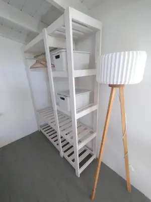 a white book shelf in a room with a stool at Schönes Loft VGB in Villa General Belgrano