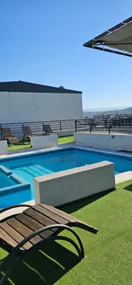 a swimming pool with a bench and chairs on a building at MIRALEJOS CENTRO op AL in Villa Carlos Paz