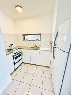 a white kitchen with a sink and a refrigerator at Dean Funes Apartamento in Cordoba