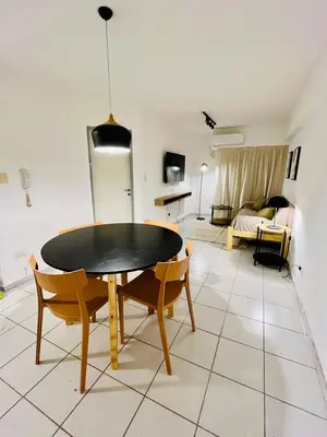 a dining room with a table and chairs and a living room at Dean Funes Apartamento in Cordoba