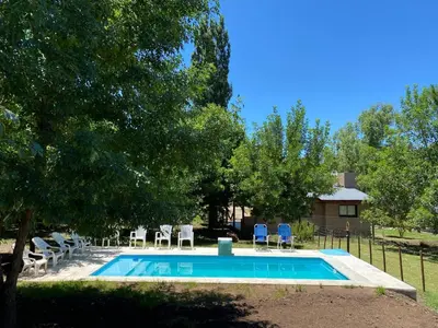 a swimming pool with chairs and a house at Cuatro vientos 2 in Santa Rosa de Calamuchita