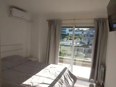 a bedroom with a bed and a large window at Veneto Village Departamento in Villa Parque Siquiman