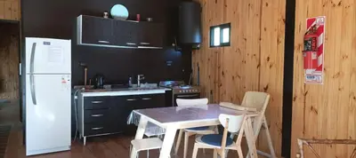 a kitchen with a table and chairs and a white refrigerator at Casita en el río, Mayu Sumaj in San Antonio de Arredondo