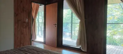 a bedroom with two large windows and a bed in it at Casita en el río, Mayu Sumaj in San Antonio de Arredondo
