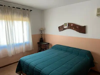 a bedroom with a green bed and a window at El fogón de los amigos in Villa Carlos Paz