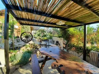 a large wooden table under a wooden pergola at El fogón de los amigos in Villa Carlos Paz