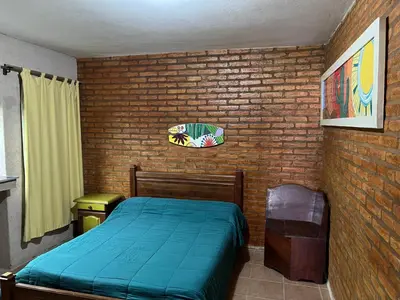 a bedroom with a blue bed and a brick wall at El fogón de los amigos in Villa Carlos Paz