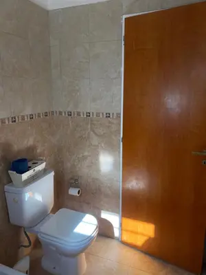 a bathroom with a toilet and a wooden door at Casa Ayacucho in Alta Gracia