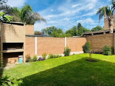 a backyard with a brick wall and a grass yard at Casa Ayacucho in Alta Gracia