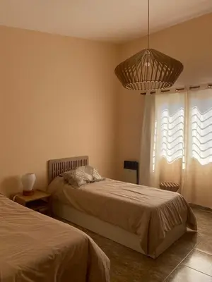 a bedroom with two beds and a chandelier at Casa Ayacucho in Alta Gracia