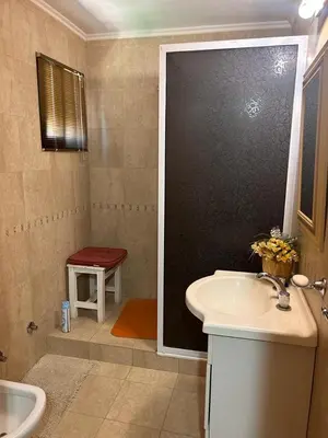a bathroom with a sink and a shower with a red stool at El Recuerdo in Merlo