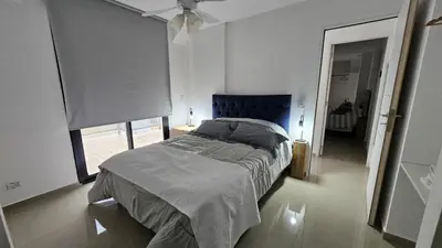 a bedroom with a bed with a blue headboard and a window at Penthouse Calazans in Cordoba